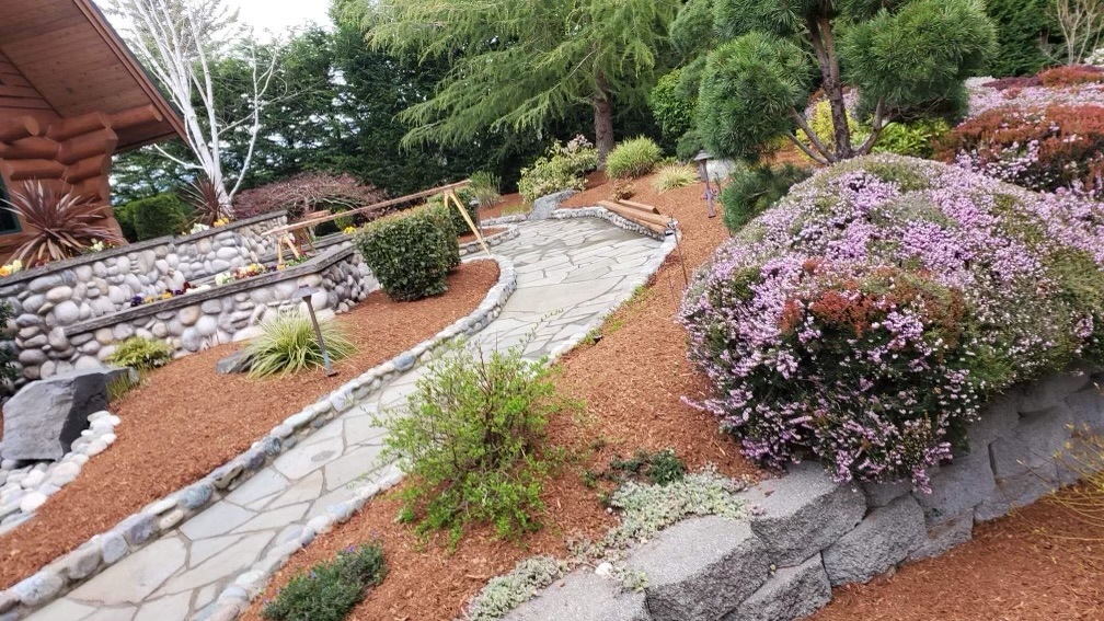Stone garden pathways, flowering shrubs and landscaped beds from River Rock’s project gallery