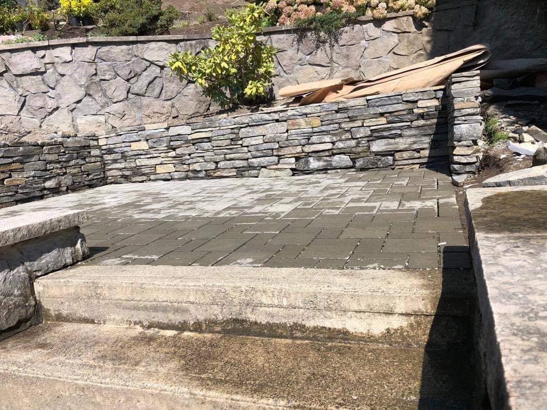 Stone retaining walls and a paved patio shown in River Rock’s project gallery
